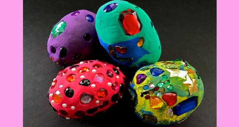 4 multicolored eggs covered in purple, green, red, and yellow clay. Decorated with gems. 