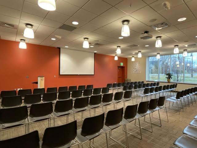 Large room with chairs set-up theater style, projector screen on wall